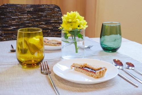 a table with a plate of food and a vase with yellow flowers at Dolcevita guest house in Torreano