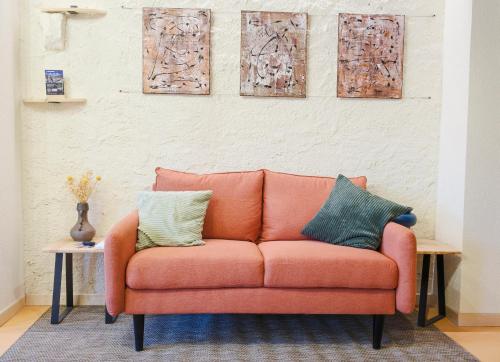 an orange couch in a room with paintings on the wall at Dolcevita guest house in Torreano