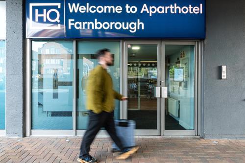 a man walking down a sidewalk in front of a store at HQ Aparthotel Farnborough in Farnborough