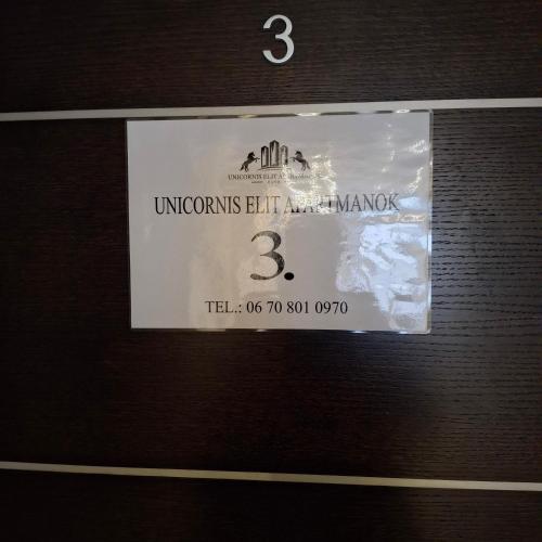 a sign on the side of a wooden door at Unicorniselit Apartmanok in Eger
