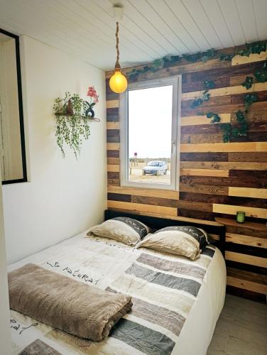 un lit dans une chambre avec un mur en bois dans l'établissement Appartement face mer 4 personnes linge de maison et papier toilette non fournis, à Saint-Hilaire-de-Riez