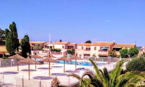 - une piscine avec des parasols en paille et un complexe dans l'établissement Appart 2 pièces 4 couchages PORT LEUCATE NATURISME PL010-843, à Port-Leucate
