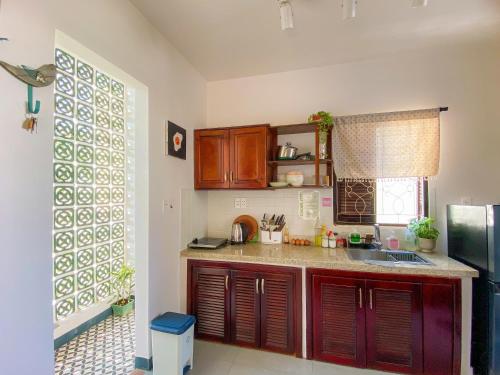a kitchen with wooden cabinets and a sink and a window at DƯỚI TÁN CÂY homestay in Tây Ninh