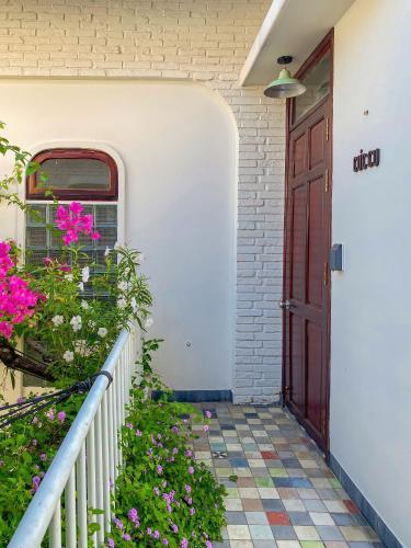 a front door of a house with flowers at DƯỚI TÁN CÂY homestay in Tây Ninh