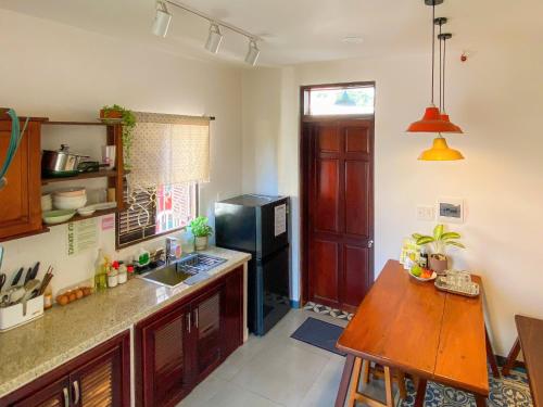 a kitchen with a wooden table and a black refrigerator at DƯỚI TÁN CÂY homestay in Tây Ninh