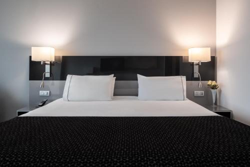 a bedroom with a bed with two pillows and two lamps at Eurostars Palace in Córdoba