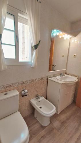 a bathroom with a toilet and a sink and a mirror at Pareada con piscina privada y con vistas in Comarruga