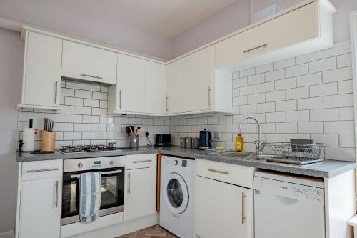 a kitchen with white cabinets and a washer and dryer at Host & Stay - Cannon Apartment in Worcester