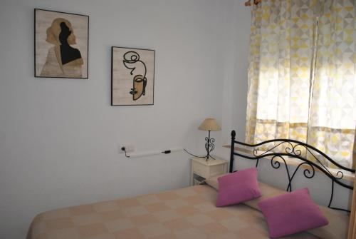 a bedroom with a bed with purple pillows and a window at Oasis Playa de Gandía in Gandía