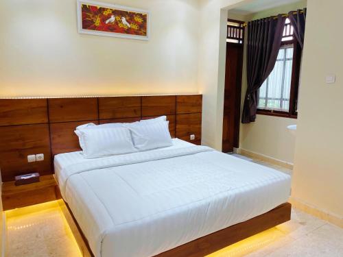 a bedroom with a large white bed and a window at ndalem singgah malioboro by abiza in Demangan