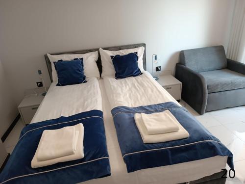 a bedroom with two beds and a chair at Cobalt Apartments in Mikołajki