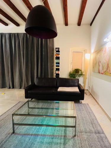 a living room with a black couch and a glass table at ARTvacanza Atelierhaus Edenkoben in Edenkoben