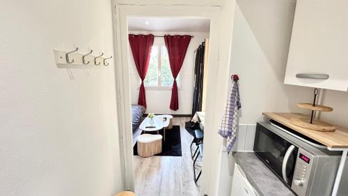 Cette petite chambre dispose de rideaux rouges et d'une table. dans l'établissement Studio cosy Aix les Bains, à Aix-les-Bains