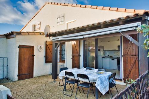 une terrasse avec une table et des chaises dans une maison dans l'établissement F3 house with terrace on the seafront, à Leucate