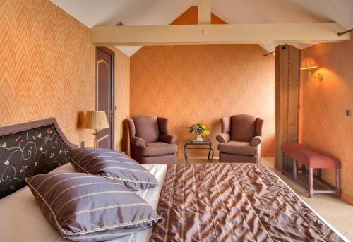 a bedroom with a bed and two chairs at Domaine de Rochevilaine in Billiers