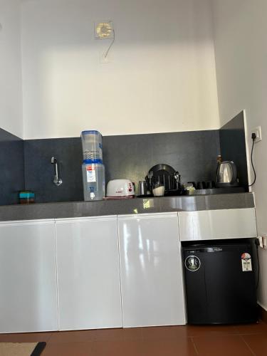 a kitchen with white cabinets and a black counter top at Mahogany by Exuberance Stays in Wayanad