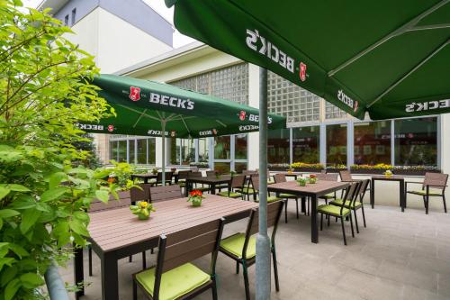 a restaurant with tables and chairs with green umbrellas at Familienhotel Citylight in Berlin