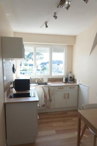 une cuisine avec des armoires blanches et un comptoir dans l'établissement Appartement rénové proche de la plage, à Bénodet