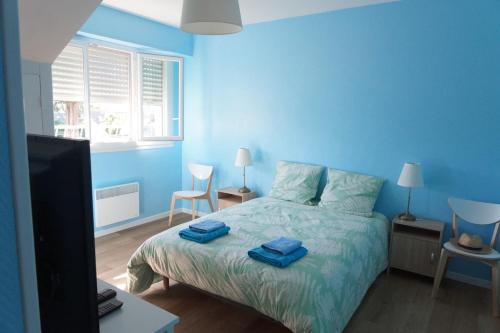 - une chambre bleue avec un lit et 2 serviettes dans l'établissement Appartement rénové proche de la plage, à Bénodet