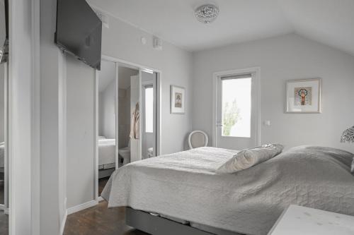 a white bedroom with a bed and a television at Villa Lumikontupa in Jyväskylä