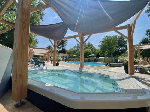 a hot tub in a patio with an umbrella at ZEcamping 4 étoiles familial avec pataugeoire et jacuzzi in Coulon
