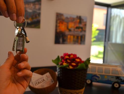 a person holding a pair of keys with a vase of flowers at Glamping Italia 90 Mini Lodges in Domaso