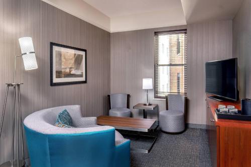 a living room with a blue chair and a tv at Courtyard Boston Copley Square in Boston