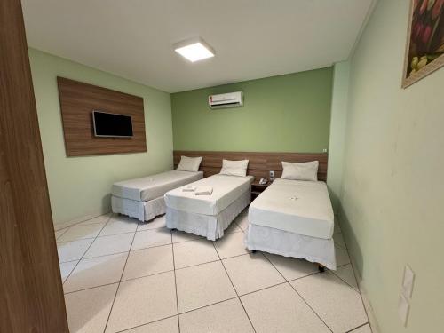 a room with two beds and a flat screen tv at Domus Hotel Cidade Nobre - Ipatinga in Ipatinga