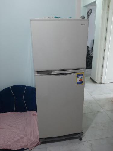a white refrigerator sitting in a room next to a wall at Minya House in Sawādah