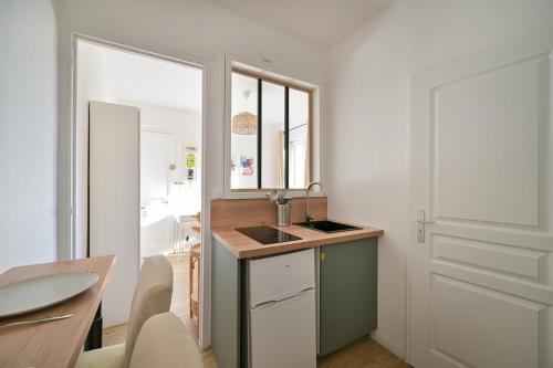 une cuisine avec un évier et un comptoir avec un miroir dans l'établissement Le petit havrais, au Havre