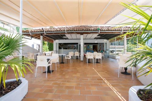 een restaurant met witte tafels, stoelen en planten bij Residenz La Selva in Ghiffa