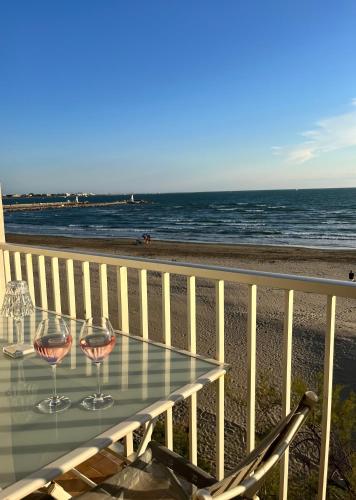 - une table avec 2 verres à vin sur la plage dans l'établissement Le Grau du Roi appartement première ligne en face de la mer, au Grau-du-Roi