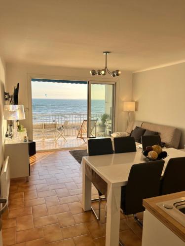 - un salon avec une table et une vue sur l'océan dans l'établissement Le Grau du Roi appartement première ligne en face de la mer, au Grau-du-Roi