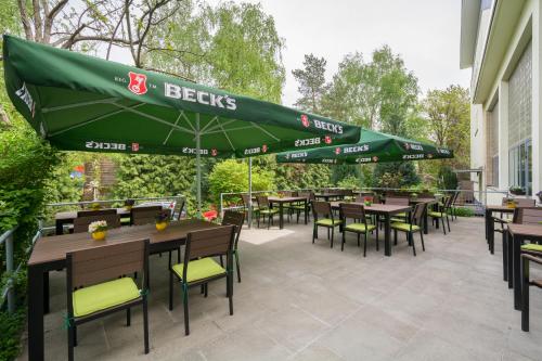 a patio with tables and chairs and a green umbrella at Familienhotel Citylight in Berlin