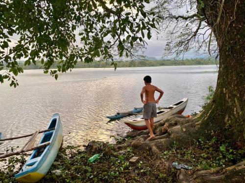 un hombre de pie junto a dos barcos en un lago en Lake Front, en Ibbagomuwa
