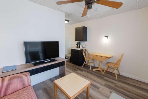 a living room with a flat screen tv and a table at Ocean House Boutique Hotel & Motel in Old Orchard Beach