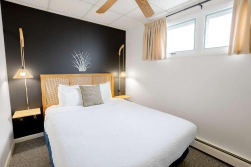 a bedroom with a white bed and two windows at Ocean House Boutique Hotel & Motel in Old Orchard Beach