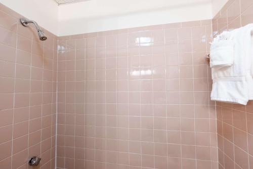 a bathroom with a shower with pink tiles and white towels at Ocean House Boutique Hotel & Motel in Old Orchard Beach