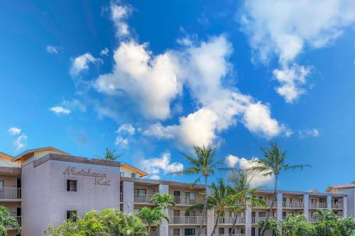 a hotel with palm trees and a blue sky at Maalaea Kai 311 in Wailuku