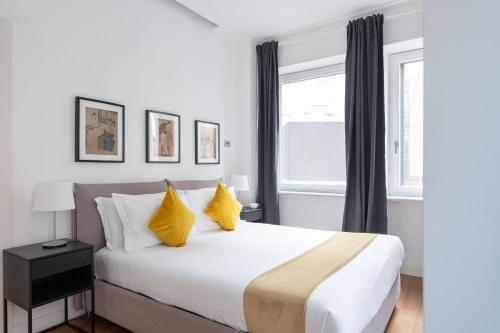a bedroom with a large white bed with yellow pillows at Heart Milan Apartments San Sepolcro Duomo in Milan