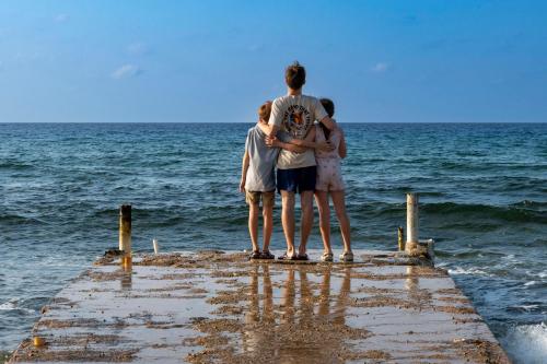 a group of people standing on a pier looking at the ocean at Featherstone Downstairs Apartment, Cayman Brac in Cayman Brac