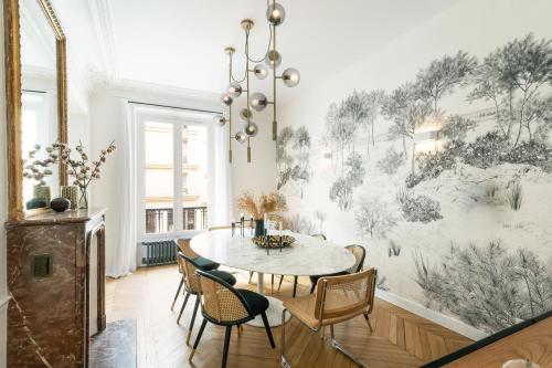 une salle à manger avec une table et des chaises ainsi qu'une fresque murale. dans l'établissement Magnifique appartement 135m2 Jardin du Luxembourg, à Paris