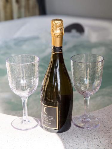 a bottle of wine and two glasses on a table at Braisty woods - Hopes & Beams in Harrogate
