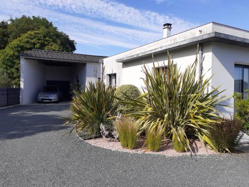 a white house with a garage and some plants at Océane in Saint-Augustin