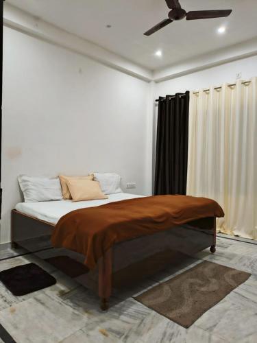 a bed in a white room with a ceiling fan at Siddhi Homestay in Varanasi