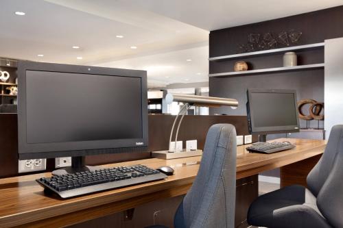 a desk with a computer monitor and two chairs at Courtyard by Marriott Boston Dedham/Westwood in Westwood