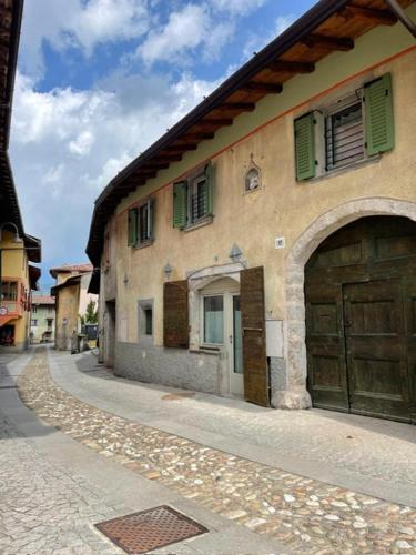 an old building with green shutters on a street at La Cà di Tonia e Abigaille in Songavazzo