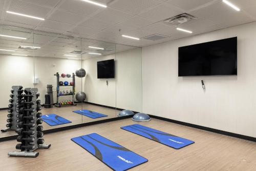 a gym with blue mats and a flat screen tv at Courtyard Charlottesville - University Medical Center in Charlottesville