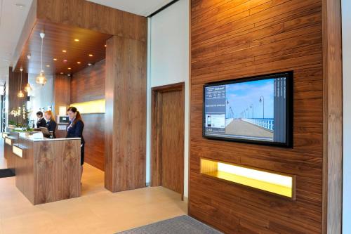 a lobby with a tv on a wooden wall at Courtyard by Marriott Gdynia Waterfront in Gdynia