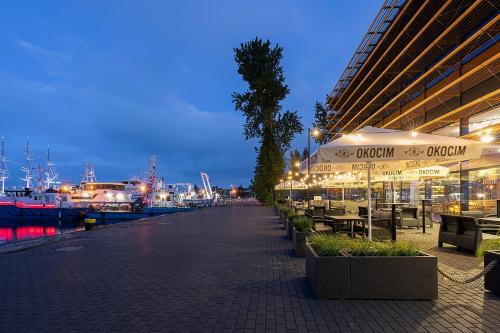 a marina at night with tables and chairs and boats at Courtyard by Marriott Gdynia Waterfront in Gdynia